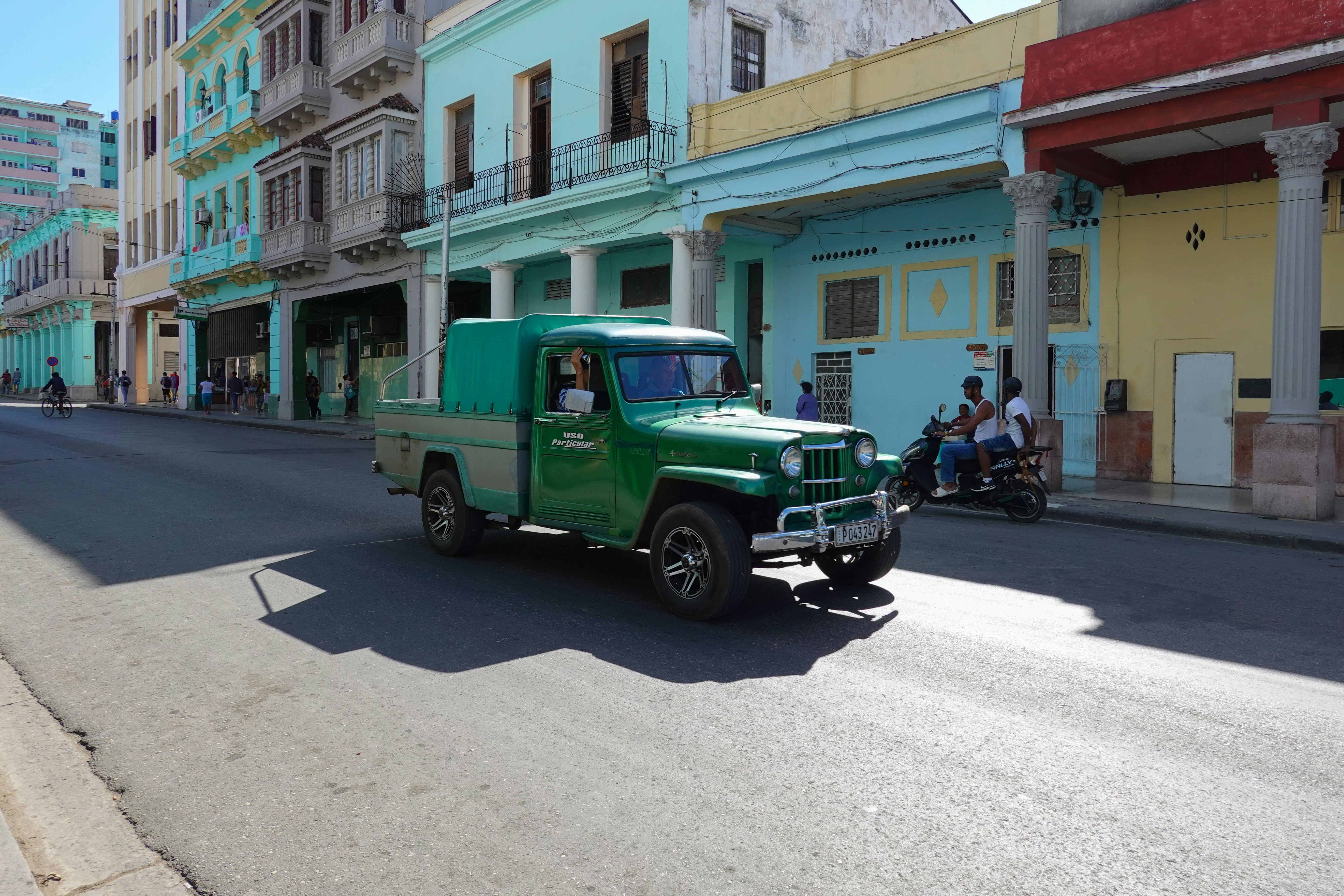 green single cab pickup truck parked near green and white concrete building during daytime